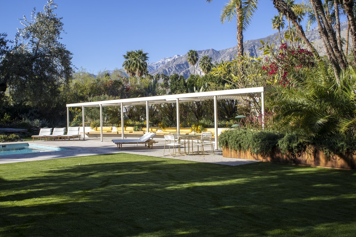 Post-and-beam pavilion of the Koerner House opening to the lawn and pool with the San Jacinto Mountains behind