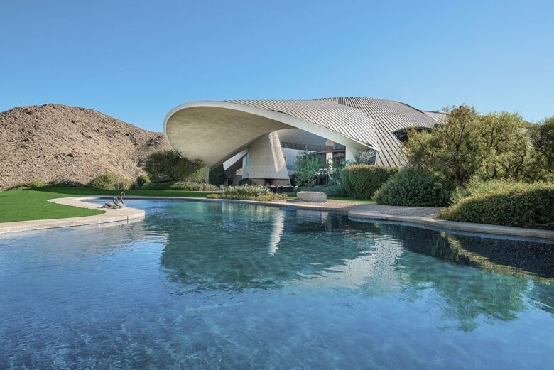 Hope Estate - daytime exterior above the pool The Hope Estate in Palm Springs by day, its curved concrete and copper shell roof rising above the swimming pool with the desert hillside behind it